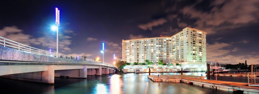 Miami condominium tower lit up at night beside the waterway