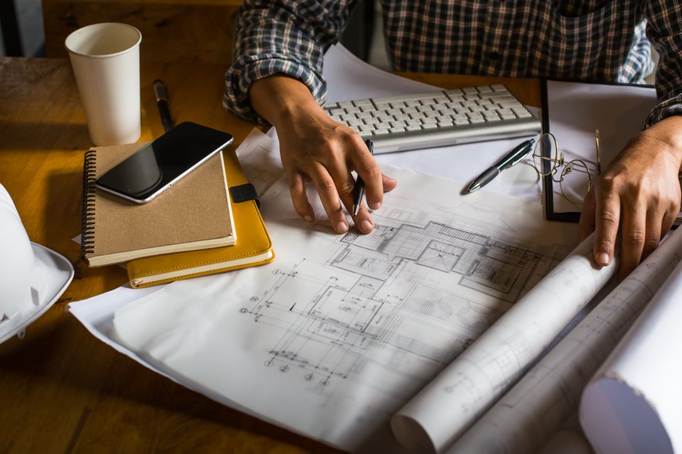 Blueprints and building plans spread across a desk, planning rebuild coverage