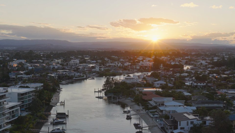 Aerial view of waterfront homes along a canal at golden sunset