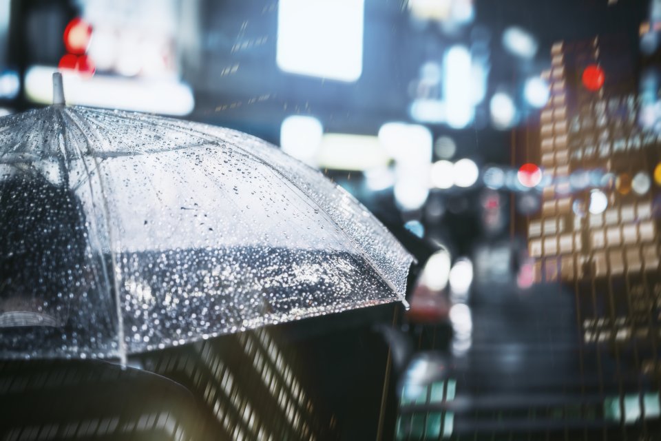 Raindrops on an umbrella against blurred city lights at night